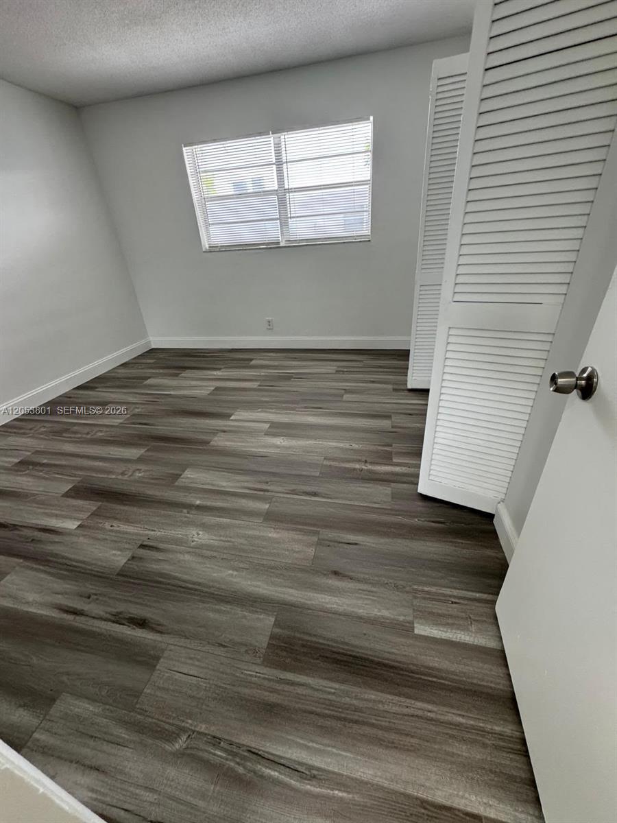 An empty room features gray wood-look flooring, white walls, and a white louvered closet door — 2435 Van Buren St APT 2B, Hollywood FL 33020, HOLLYWOOD, FL