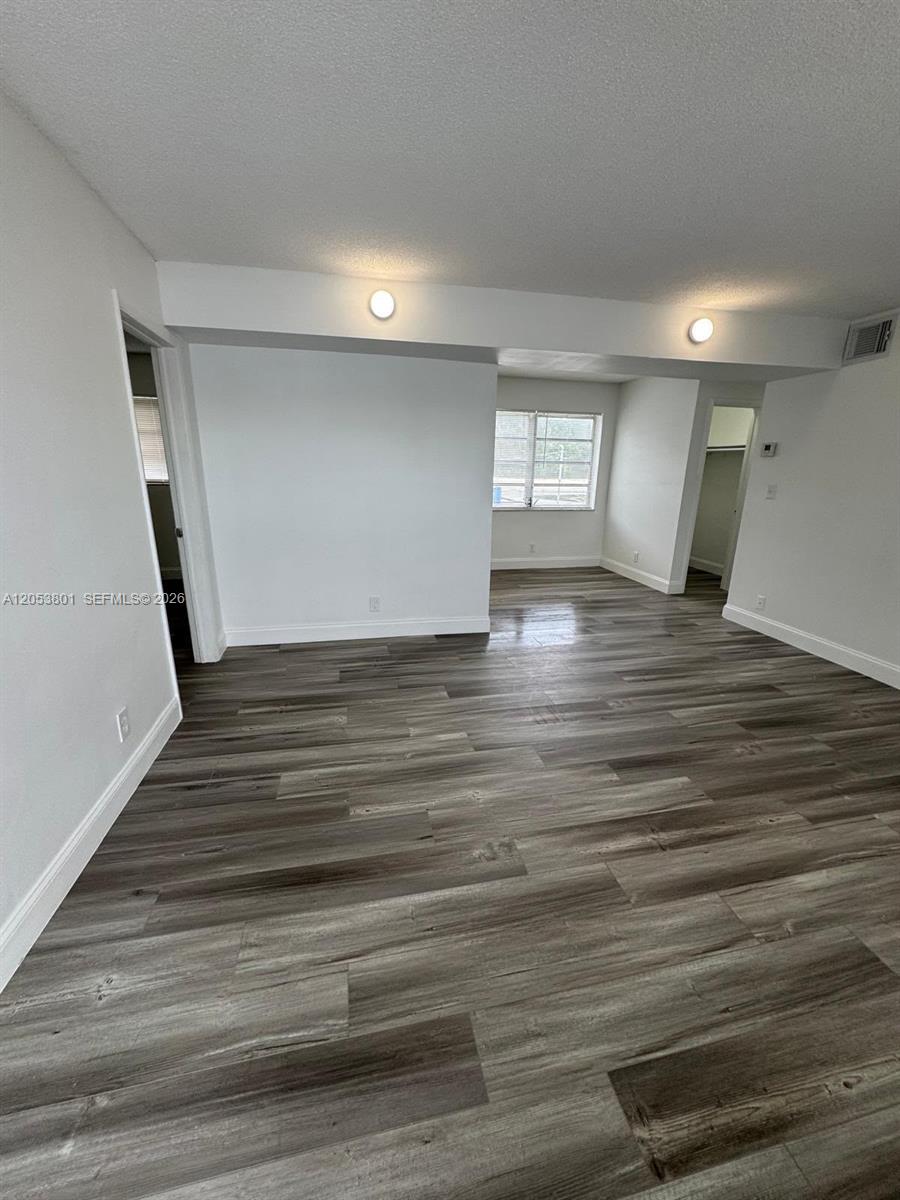 An empty room features white walls, recessed lighting, and gray wood-look laminate flooring — 2435 Van Buren St APT 2B, Hollywood FL 33020, HOLLYWOOD, FL
