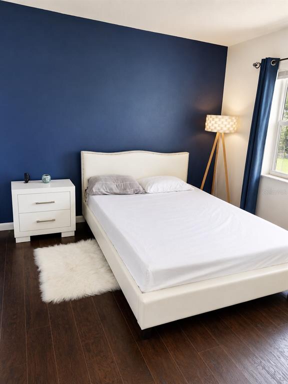 A bedroom features a white bed, a white nightstand, and a dark blue accent wall — 2850 W GOLF BOULEVARD UNIT 212, POMPANO BEACH, FL