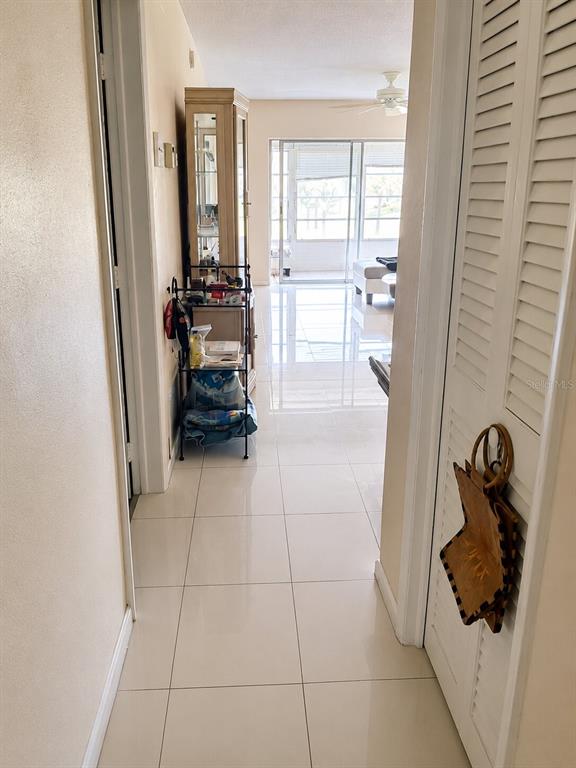 A tiled hallway leads to a living area with a glass sliding door and balcony — 2850 W GOLF BOULEVARD UNIT 212, POMPANO BEACH, FL