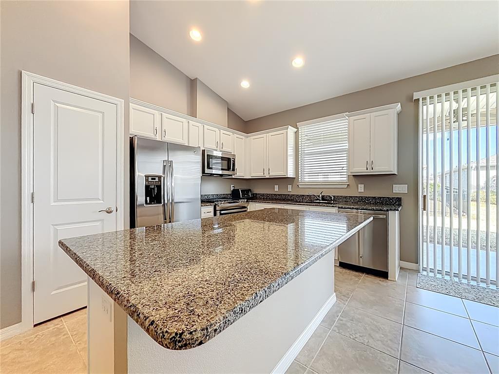 A single-story house with a beige exterior, stone accents, and a paved driveway — 5647 NW 37TH LANE ROAD, OCALA, FL