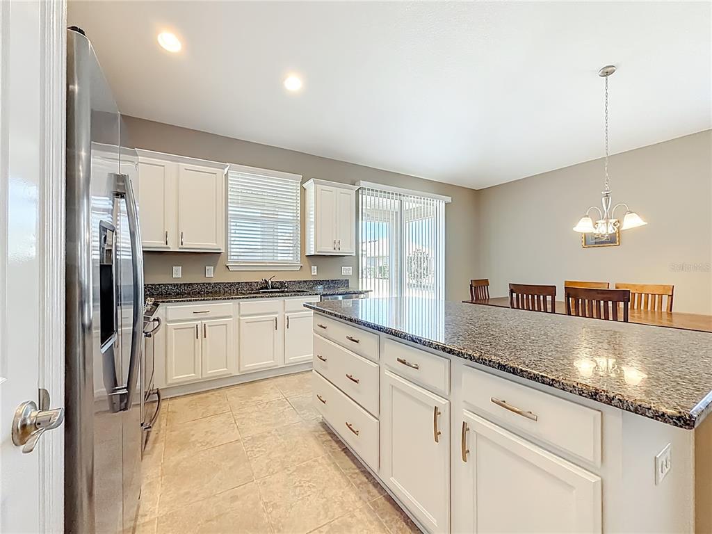 A tan house exterior features a stone-accented garage, a dark front door, and a hedge — 5647 NW 37TH LANE ROAD, OCALA, FL