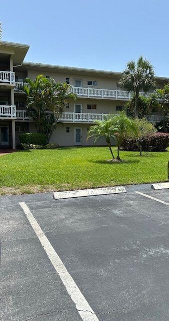 A three-story apartment building with white balconies sits behind a parking lot and grassy lawn — 2811 Garden Drive S # 107, FL 33461, FL