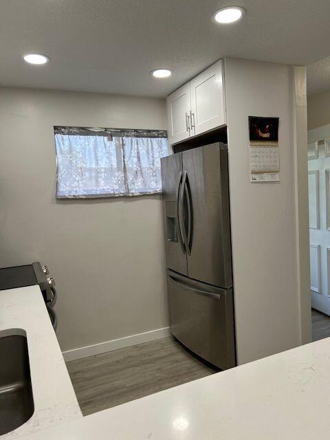 A kitchen features a stainless steel refrigerator, white cabinets, and a window with a curtain — 2811 Garden Drive S # 107, FL 33461, FL