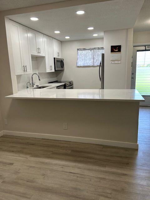 A kitchen with white cabinets, a quartz countertop, and light wood-look flooring — 2811 Garden Drive S # 107, FL 33461, FL
