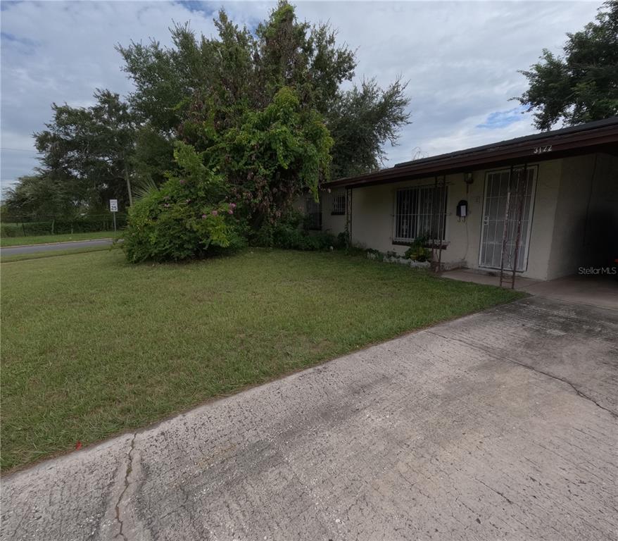 A single-story house with a concrete driveway, a front lawn, and a large overgrown tree — 3122 W SOUTH STREET, ORLANDO, FL