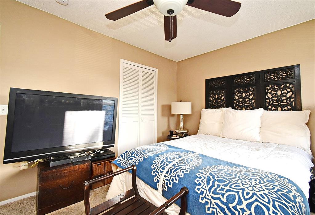 A bedroom features a bed with a decorative headboard, a ceiling fan, and a television — 686 LAKE VILLAS DRIVE UNIT 686, ALTAMONTE SPRINGS, FL