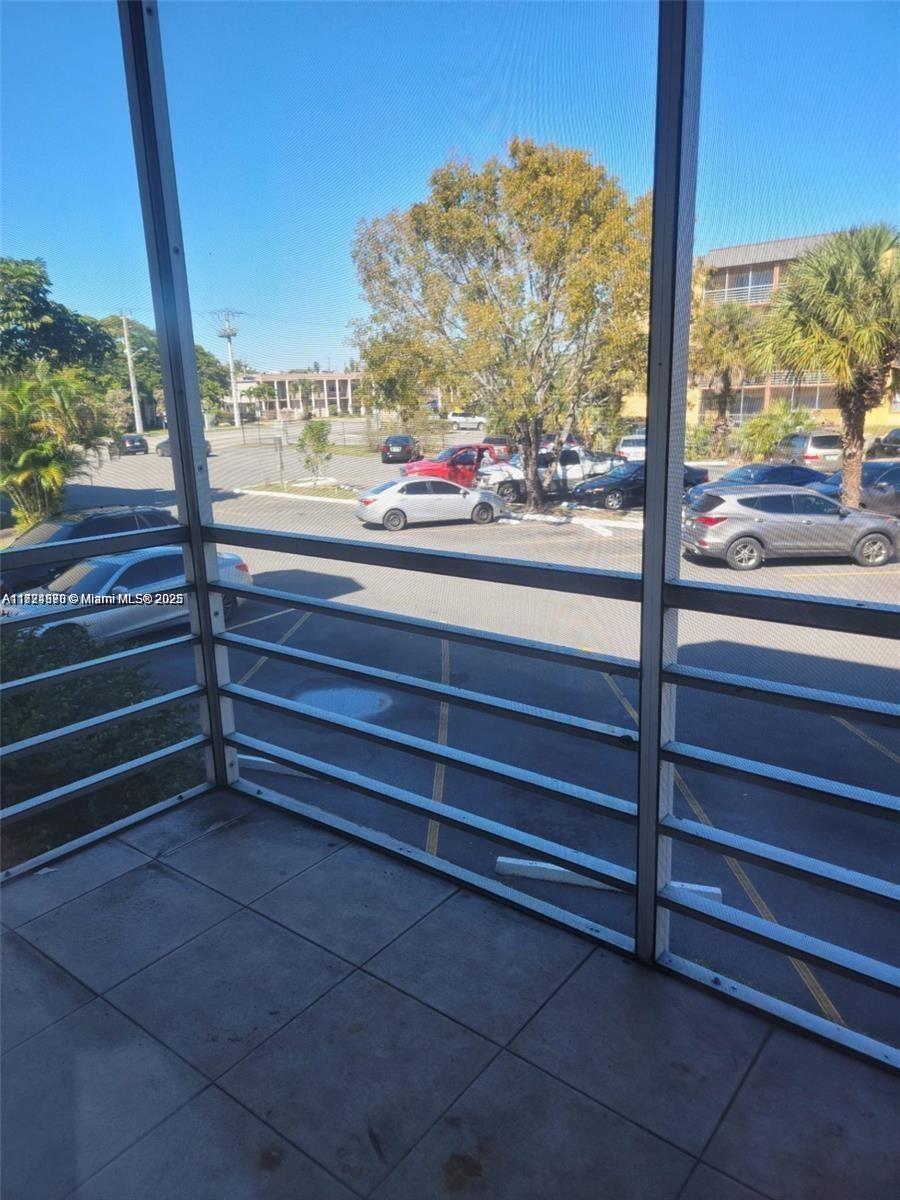 A view of a parking lot from a screened-in balcony with tiled flooring — 2800 NW 56th Ave # B202, Lauderhill FL 33313, LAUDERHILL, FL