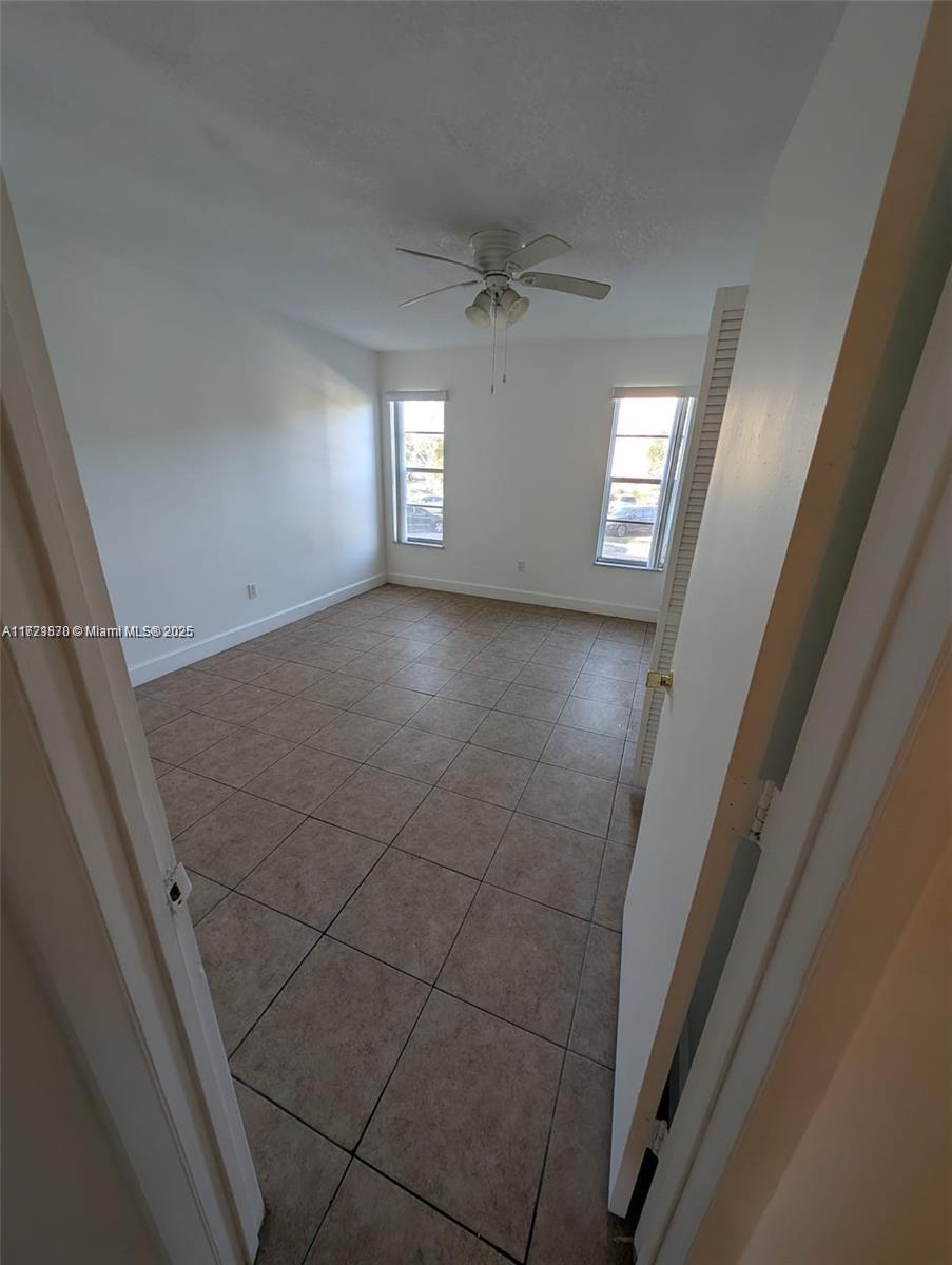 An empty bedroom features white walls, a ceiling fan, and light-colored square floor tiles — 2800 NW 56th Ave # B202, Lauderhill FL 33313, LAUDERHILL, FL