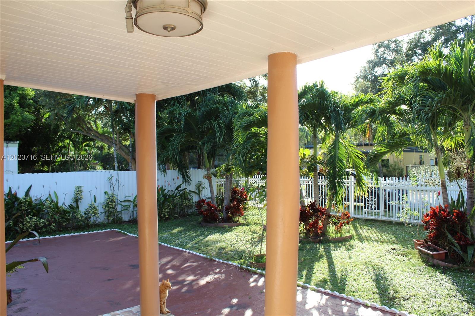 A covered patio features two tan columns, a reddish floor, and a view of a yard — 13875 NE 16th Ct, North Miami FL 33181, NORTH MIAMI, FL