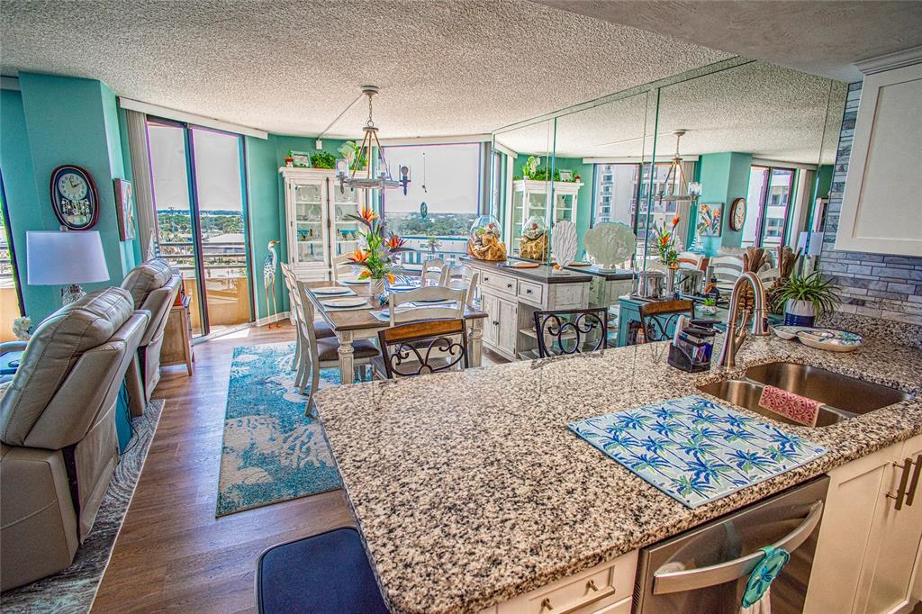 A kitchen with granite countertops overlooks a dining area and living room with floor-to-ceiling windows — 3023 S ATLANTIC AVENUE UNIT 507, DAYTONA BEACH SHORES, FL