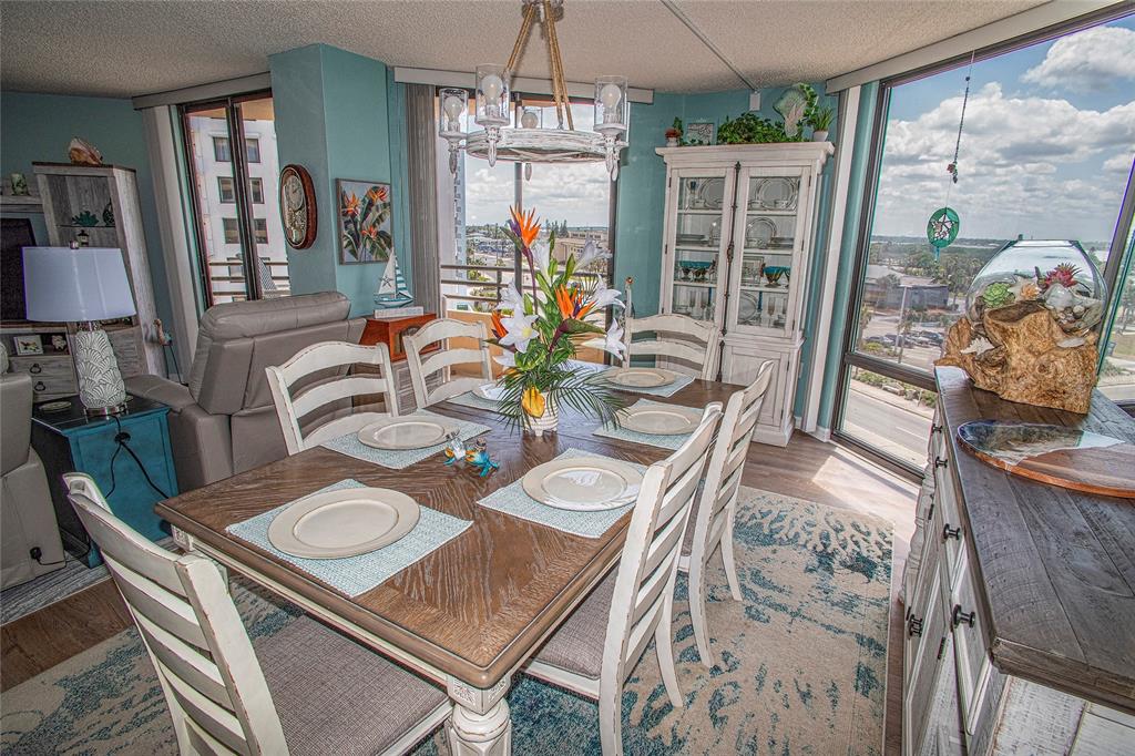 A dining room features a wooden table, white chairs, a chandelier, and large floor-to-ceiling windows — 3023 S ATLANTIC AVENUE UNIT 507, DAYTONA BEACH SHORES, FL