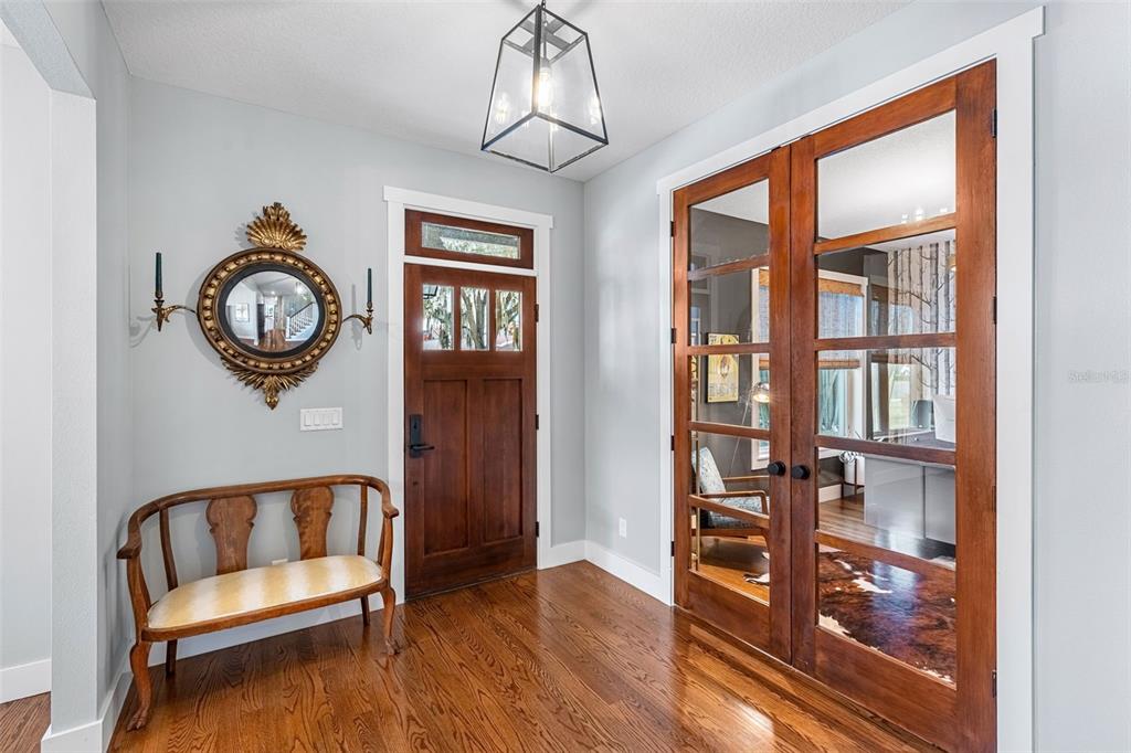 An entryway features hardwood floors, a wooden front door, and a console table with art — 2501 WINTER PARK ROAD, WINTER PARK, FL