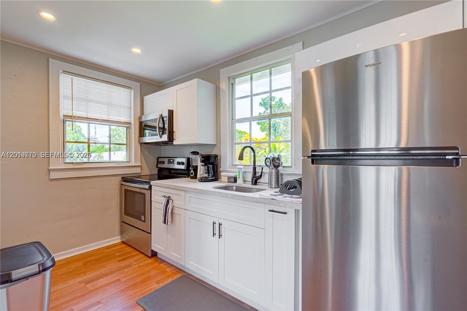 A kitchen features white cabinets, stainless steel appliances, a window, and hardwood flooring — 227 SW 30th Ave # B, Miami FL 33135, MIAMI, FL