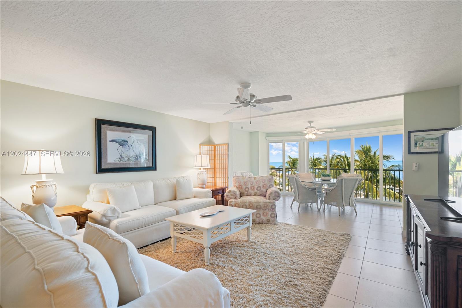 A living room with white sofas, a patterned armchair, and a balcony overlooking the ocean — 87851 Old Hwy # M42, Islamorada FL 33036, ISLAMORADA, FL