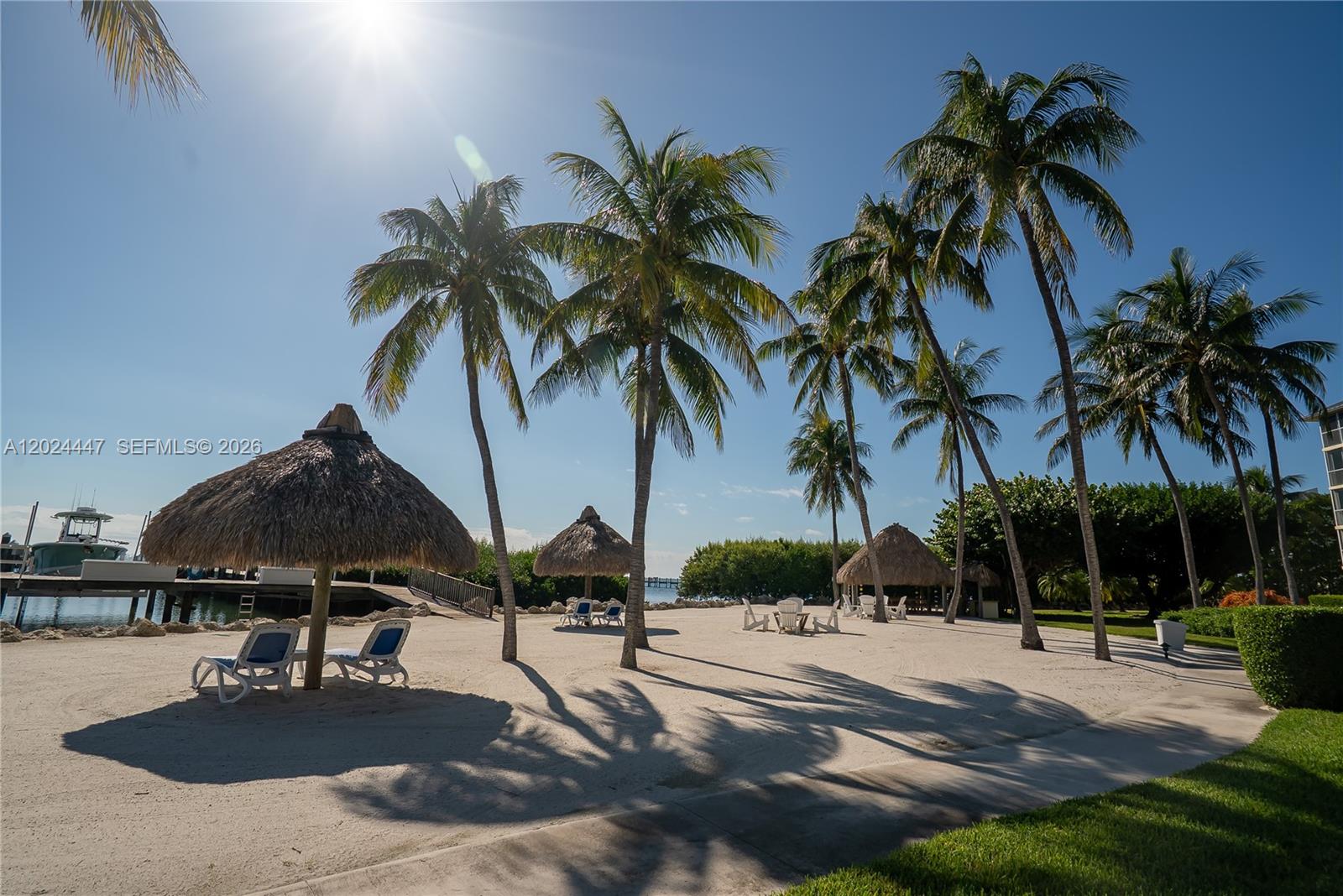 A sandy beach area features several tiki huts, palm trees, and lounge chairs — 87851 Old Hwy # M42, Islamorada FL 33036, ISLAMORADA, FL