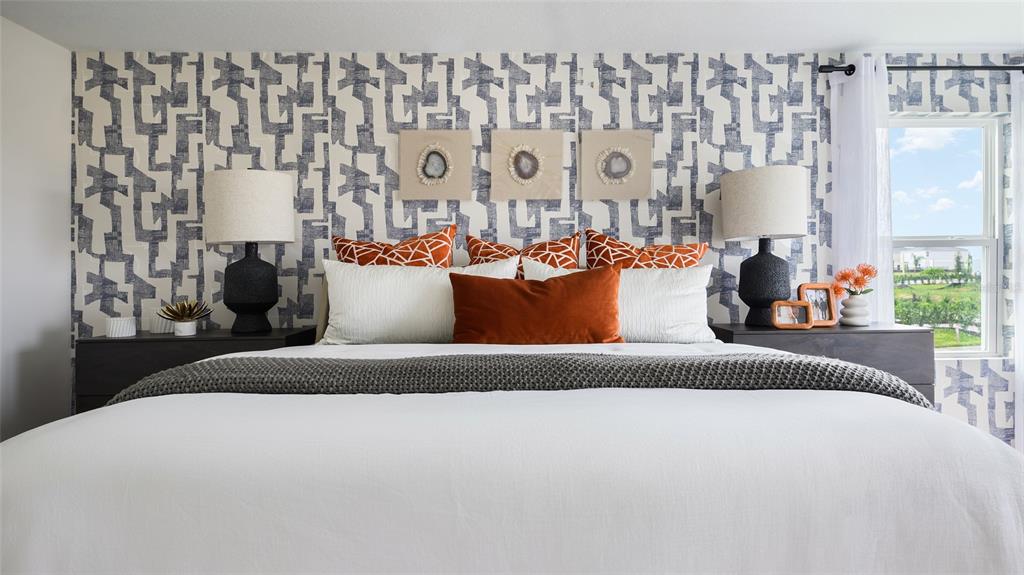 A bedroom features a patterned blue and white accent wall behind a bed with orange pillows — 4151 RIVER BEACON BOULEVARD, DAVENPORT, FL