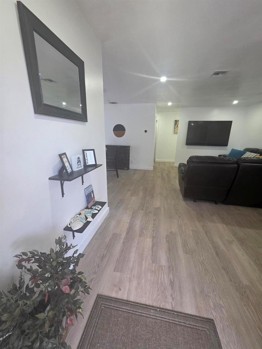 A living room features light wood-look flooring, white walls, and two wall-mounted display shelves — 320 Sterling Avenue, Delray Beach FL 33444, DELRAY BEACH, FL