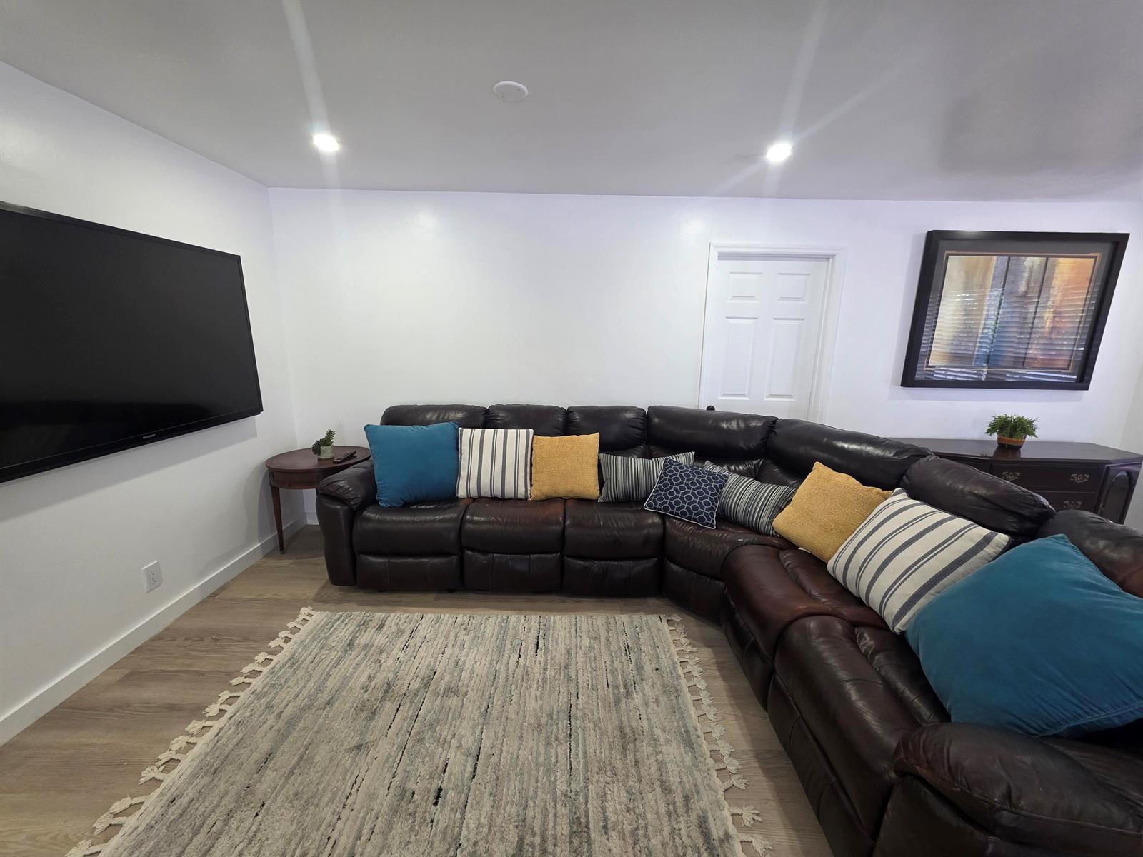 A living room features a large dark leather sectional, a television, and a textured rug — 320 Sterling Avenue, Delray Beach FL 33444, DELRAY BEACH, FL