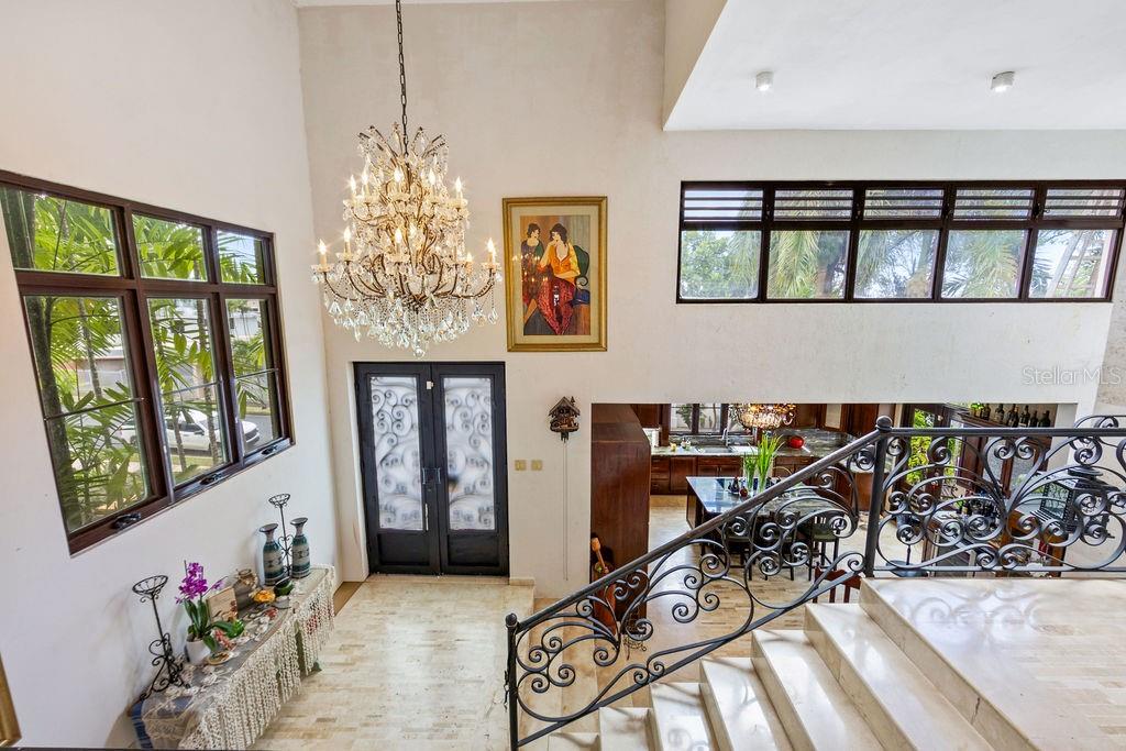 A grand foyer features a crystal chandelier, marble stairs, and a view into the kitchen — 1889 ORQUIDEA, SAN JUAN, PR