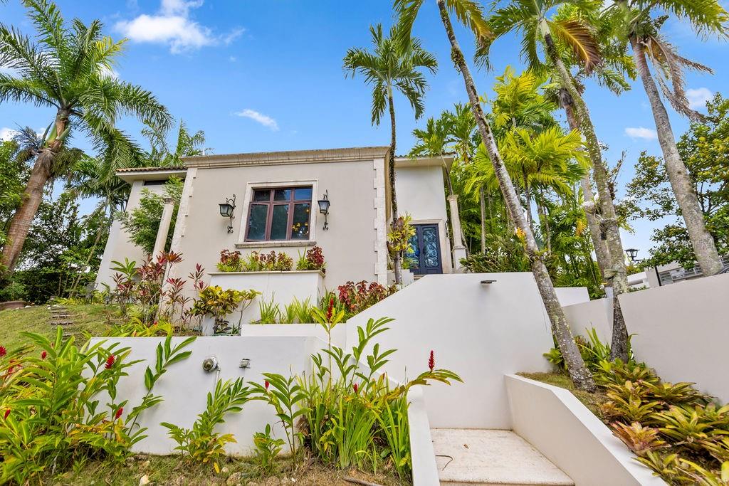 A beige house with a terraced garden, palm trees, and white concrete stairs leading upward — 1889 ORQUIDEA, SAN JUAN, PR