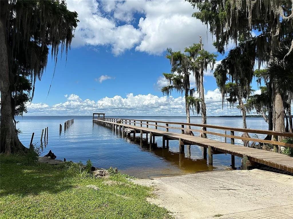 A long wooden pier extends into a calm lake surrounded by trees with Spanish moss — 817 PARADISE BOULEVARD, GEORGETOWN, FL