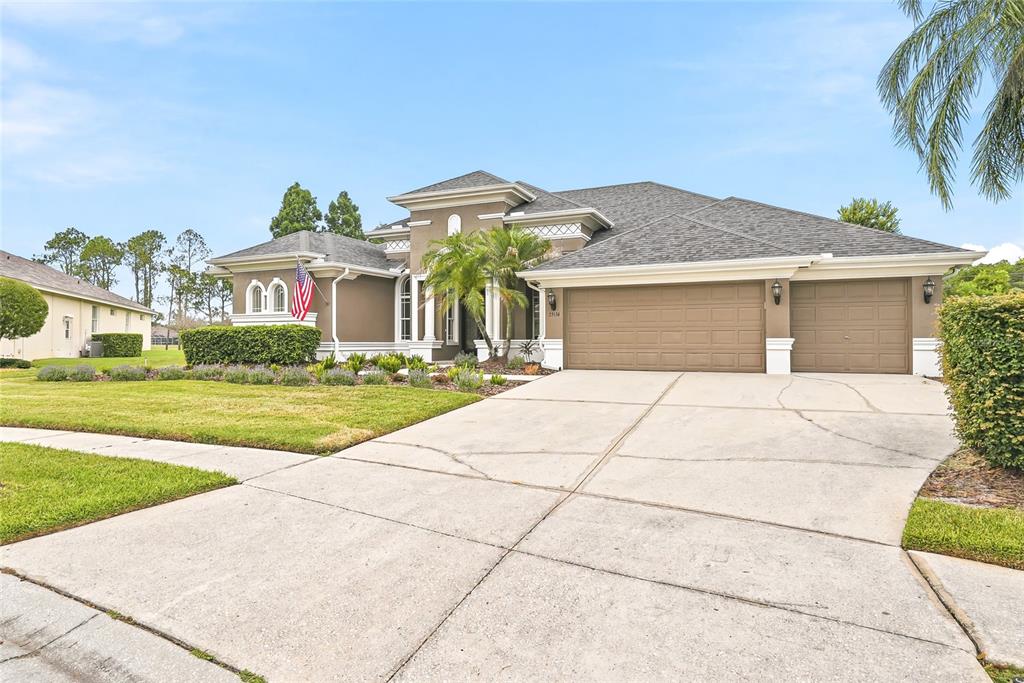 A single-story house with a brown exterior, a three-car garage, and a concrete driveway — 23534 GRACEWOOD CIRCLE, LAND O LAKES, FL