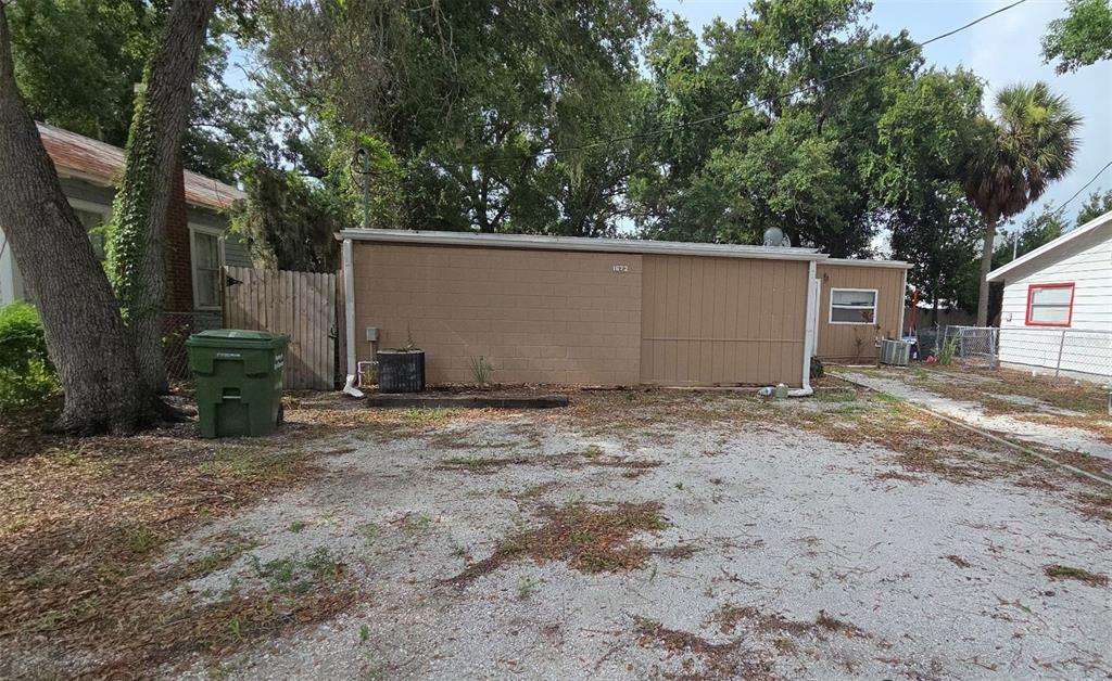 A tan, single-story building with a gravel driveway and a green trash bin outside — 1672 10TH STREET, SARASOTA, FL