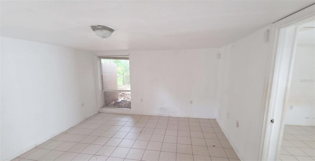 An empty room with white walls, beige tile flooring, and a window looking outdoors — 1672 10TH STREET, SARASOTA, FL