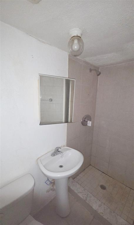 A bathroom features a pedestal sink, a wall-mounted mirror, and a tiled walk-in shower — 1672 10TH STREET, SARASOTA, FL
