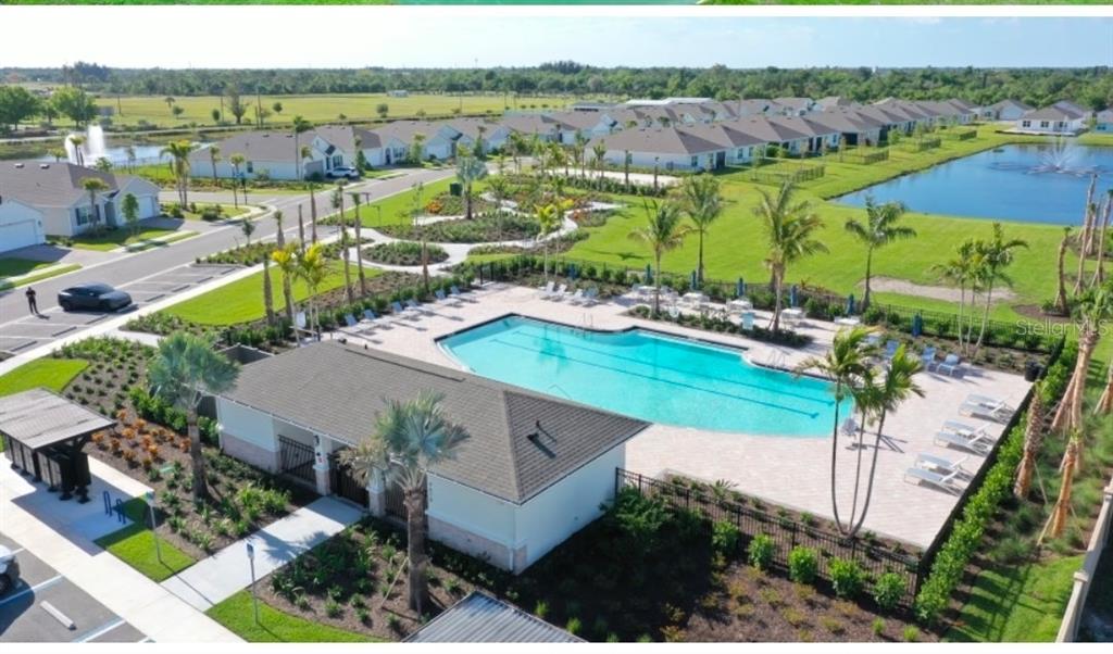An aerial view shows a community swimming pool, clubhouse, and surrounding residential homes — 9489 TURTLE GRASS CIRCLE, PUNTA GORDA, FL