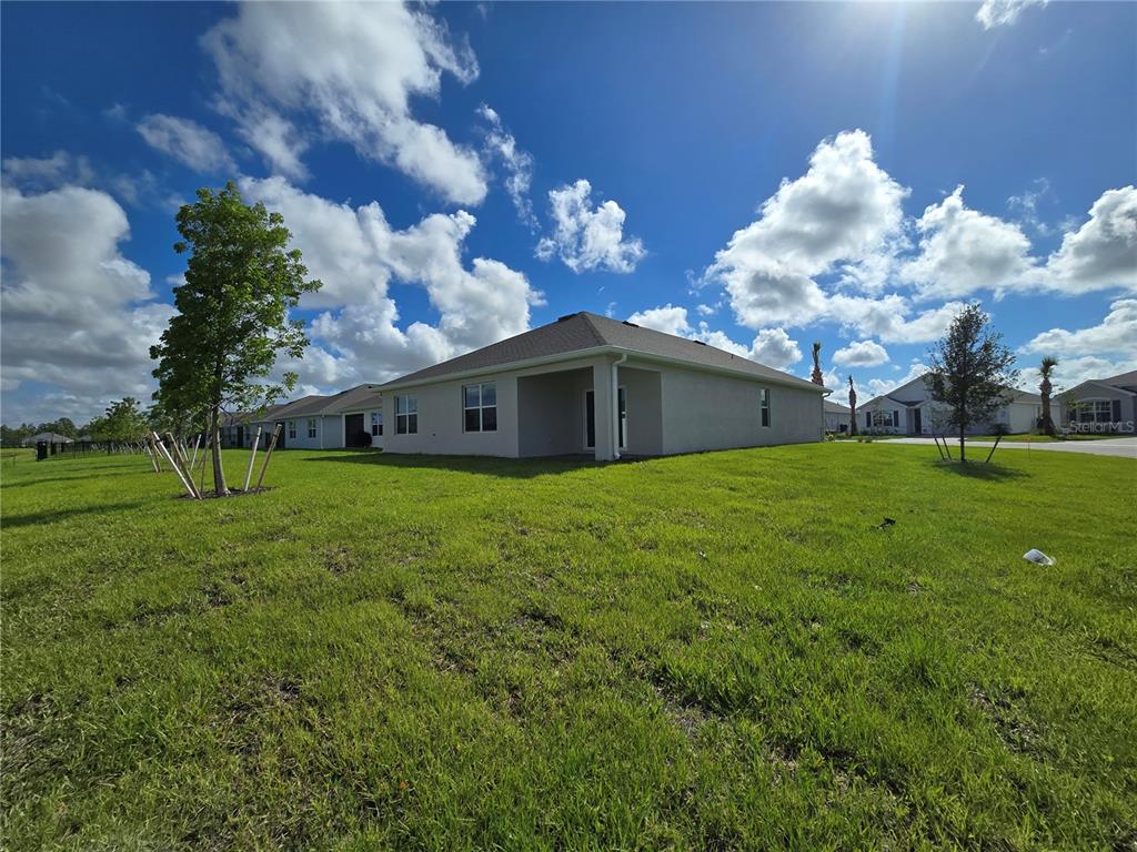 The exterior rear view of a single-story house features a covered patio and lawn — 9489 TURTLE GRASS CIRCLE, PUNTA GORDA, FL