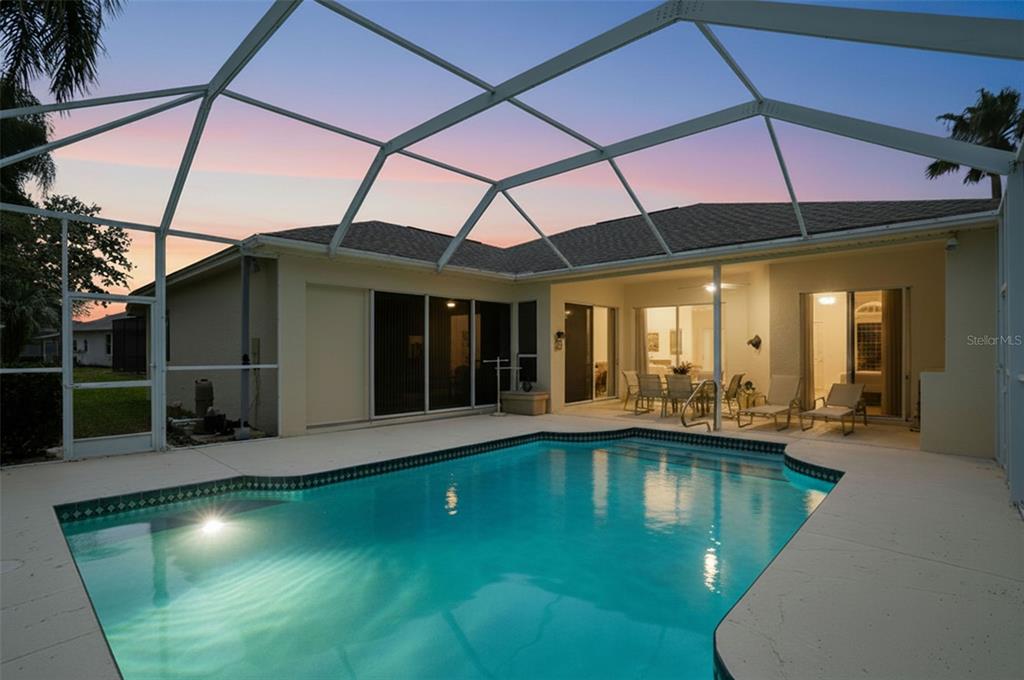 A screened-in swimming pool and patio area with outdoor seating at a residential home — 7221 ALOE DRIVE, SPRING HILL, FL