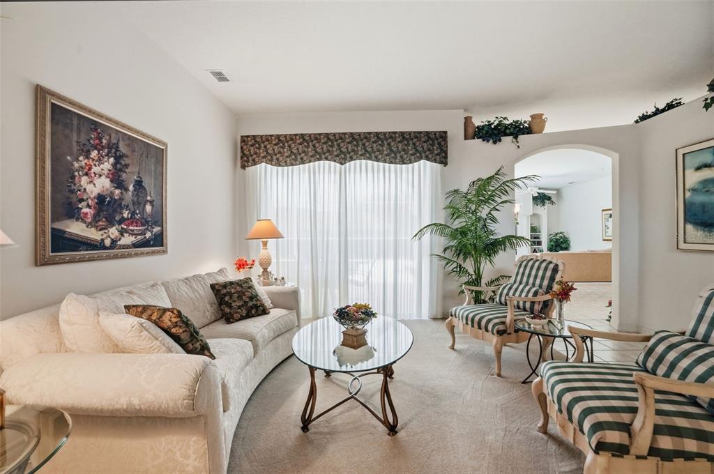 A living room features a white sofa, two striped armchairs, and a glass coffee table — 7221 ALOE DRIVE, SPRING HILL, FL