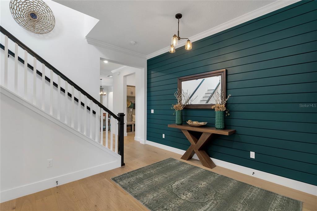 An entryway features a dark teal shiplap wall, a wooden console table, and a staircase — 17434 HONEYBELL TANGELO COURT, WINTER GARDEN, FL