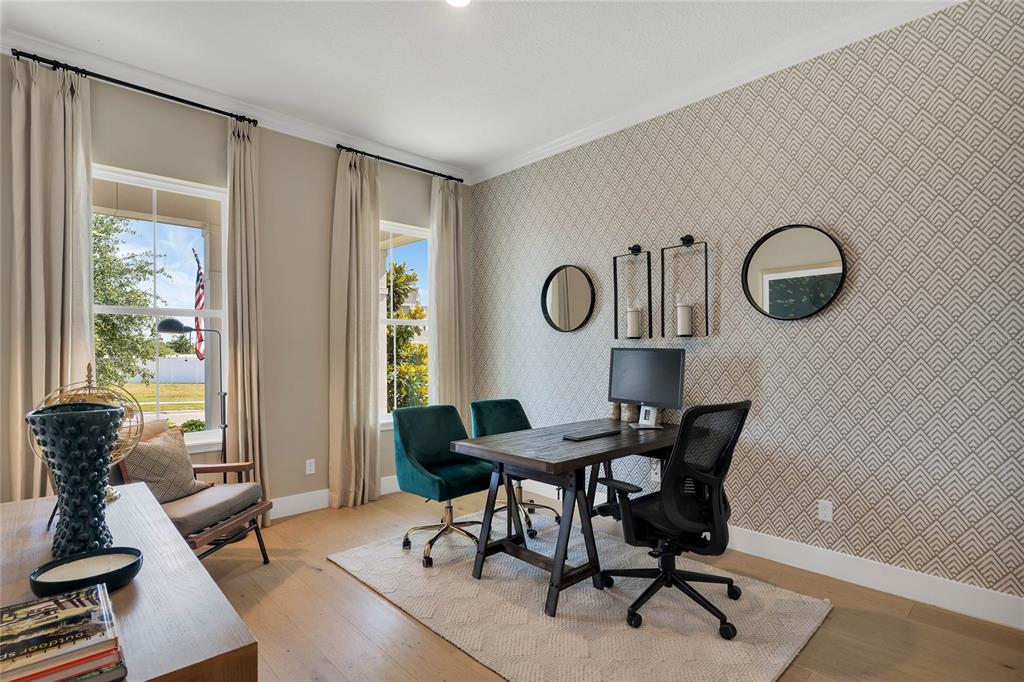 A home office features a wooden desk, two chairs, patterned wallpaper, and two large windows — 17434 HONEYBELL TANGELO COURT, WINTER GARDEN, FL