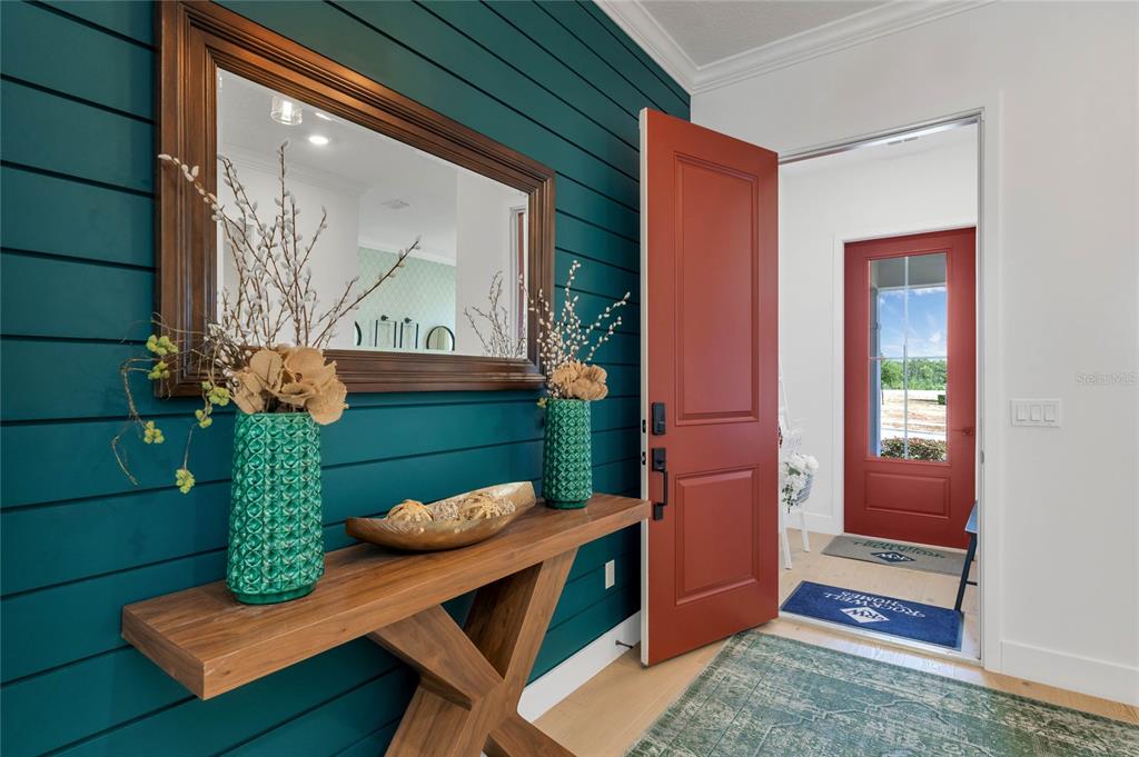 An entryway features a teal shiplap wall, a wooden console table, and a red door — 17434 HONEYBELL TANGELO COURT, WINTER GARDEN, FL