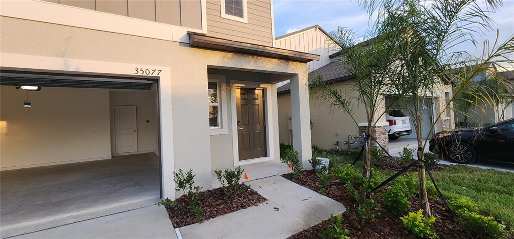 An exterior view shows a house with a garage, a front door, and landscaping — 35077 ACKLEY TRACE, ZEPHYRHILLS, FL