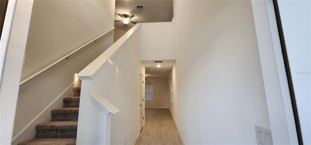 An entryway features a carpeted staircase with a white railing and light-colored tile flooring — 35077 ACKLEY TRACE, ZEPHYRHILLS, FL