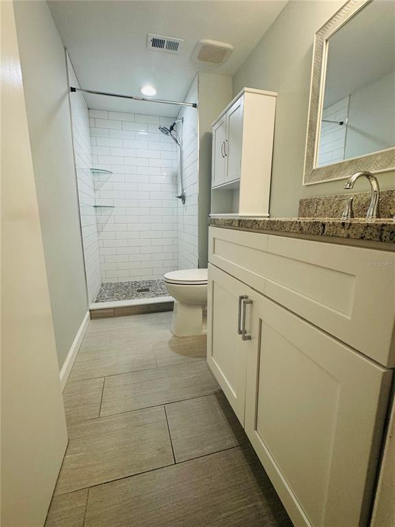 A bathroom features a tiled walk-in shower, a white vanity, and a toilet — 203 MEADOW LANE, OLDSMAR, FL