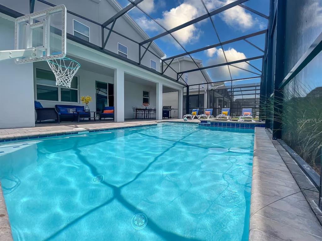 A swimming pool with a basketball hoop is enclosed by a screened lanai — 2850 BOOKMARK DRIVE, KISSIMMEE, FL