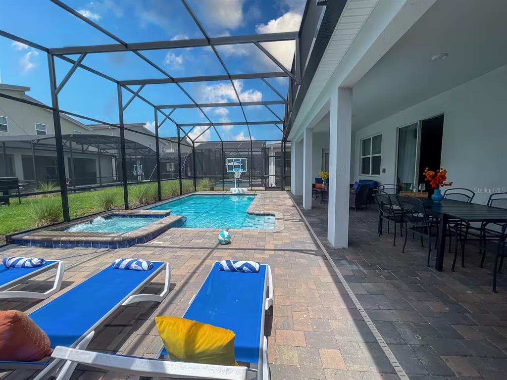 A screened-in patio features a swimming pool, a hot tub, and outdoor dining furniture — 2850 BOOKMARK DRIVE, KISSIMMEE, FL