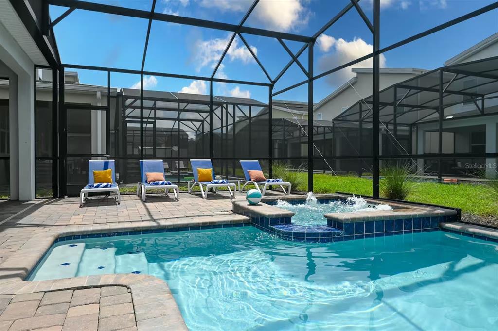 A screened-in patio features a swimming pool with an attached hot tub and lounge chairs — 2850 BOOKMARK DRIVE, KISSIMMEE, FL