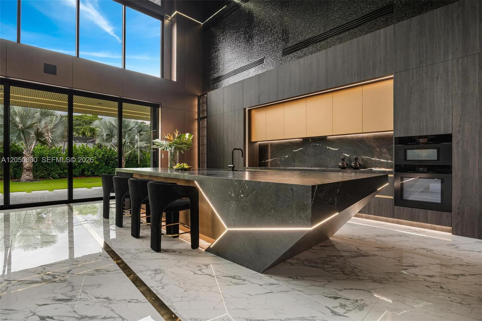 A modern kitchen features a large geometric stone island with integrated lighting and marble flooring — 13500 SW 69th Ave, Pinecrest FL 33156, PINECREST, FL