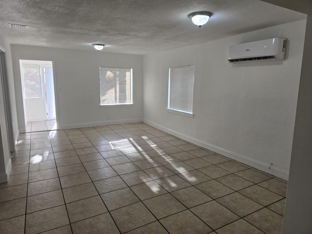 A bright, empty living room features white walls, tile flooring, two windows, and a wall-mounted AC — 5431 NW 30th Avenue, Miami FL 33142, MIAMI, FL