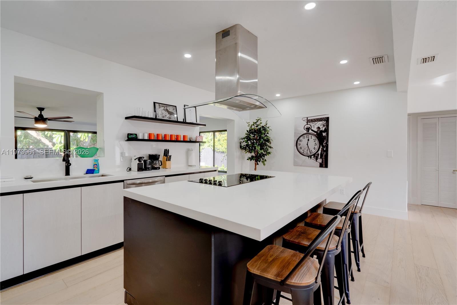 A modern kitchen features a large white island, dark cabinetry, and a stainless steel range hood — 347 NE 110th St, Miami FL 33161, MIAMI, FL