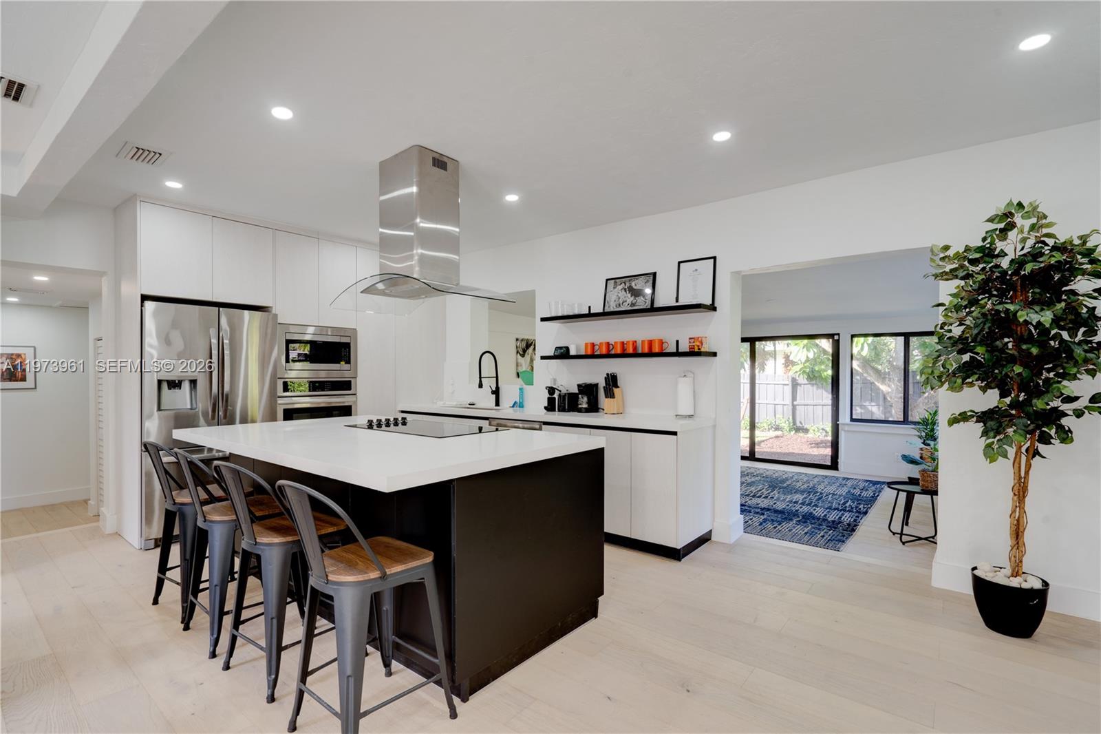A modern kitchen features a large black island, white cabinetry, and stainless steel appliances — 347 NE 110th St, Miami FL 33161, MIAMI, FL