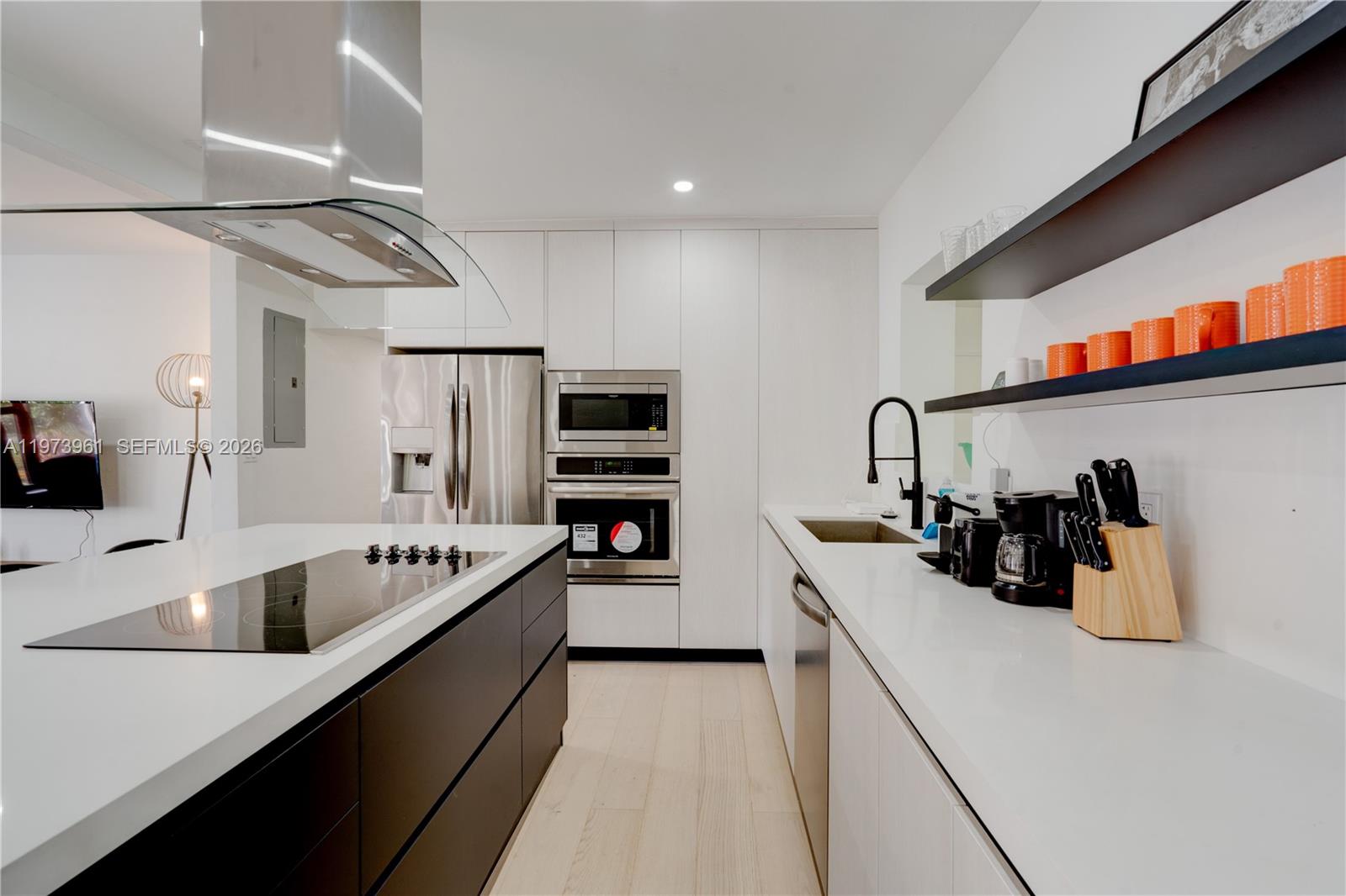 A modern kitchen features a black island, white cabinetry, stainless steel appliances, and open shelving — 347 NE 110th St, Miami FL 33161, MIAMI, FL