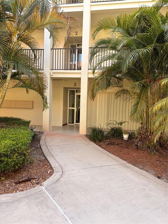 A concrete walkway leads to the entrance of a two-story building labeled block 2 — 2700 BAYSHORE BOULEVARD UNIT 2105, DUNEDIN, FL