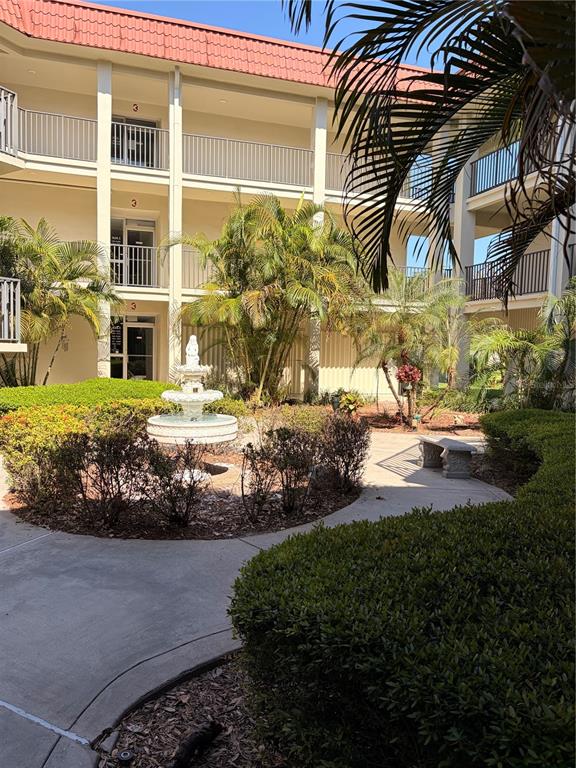 A multi-story apartment building exterior features a central courtyard with a tiered stone fountain — 2700 BAYSHORE BOULEVARD UNIT 2105, DUNEDIN, FL